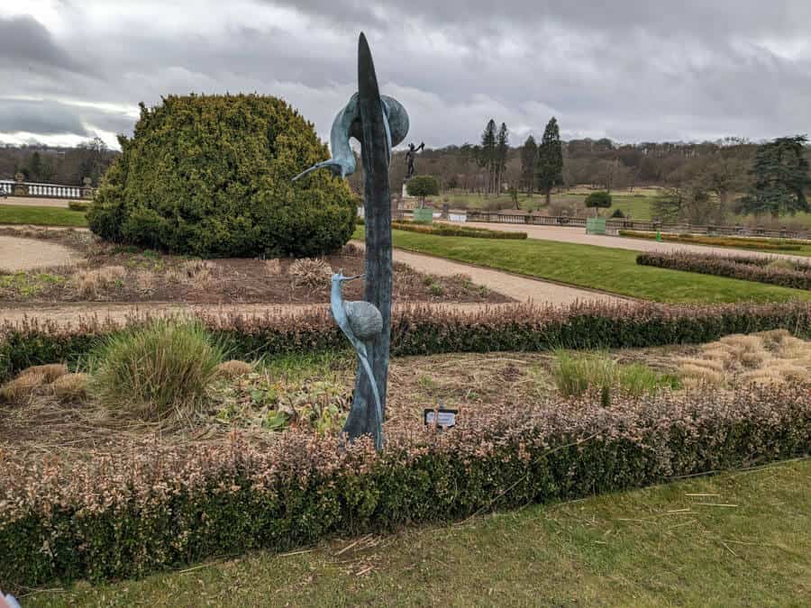 Metal snail sculpture in formal gardens