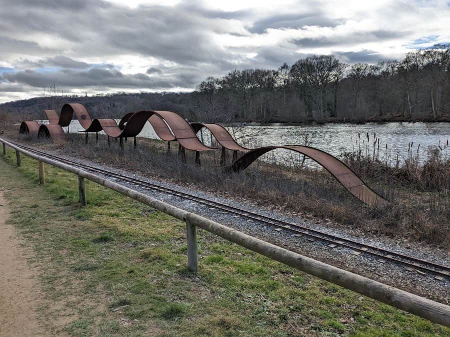 Large wave sculpture beside a lake
