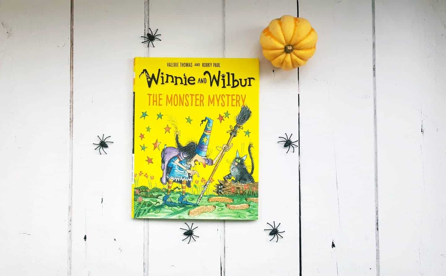 Winnie and wilbur book on white floor boards with pretent spiders and mini pumpkin