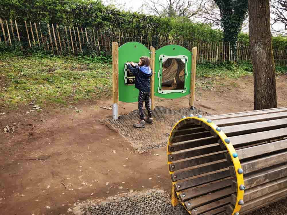 Child in playground near green framed mirror