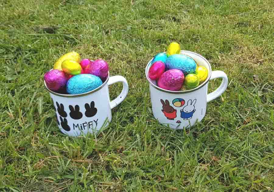 Two enamel Miffy mugs full of brightly coloured foil wrapped Easter eggs