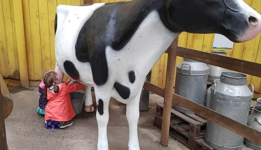 Two children milking a model cow