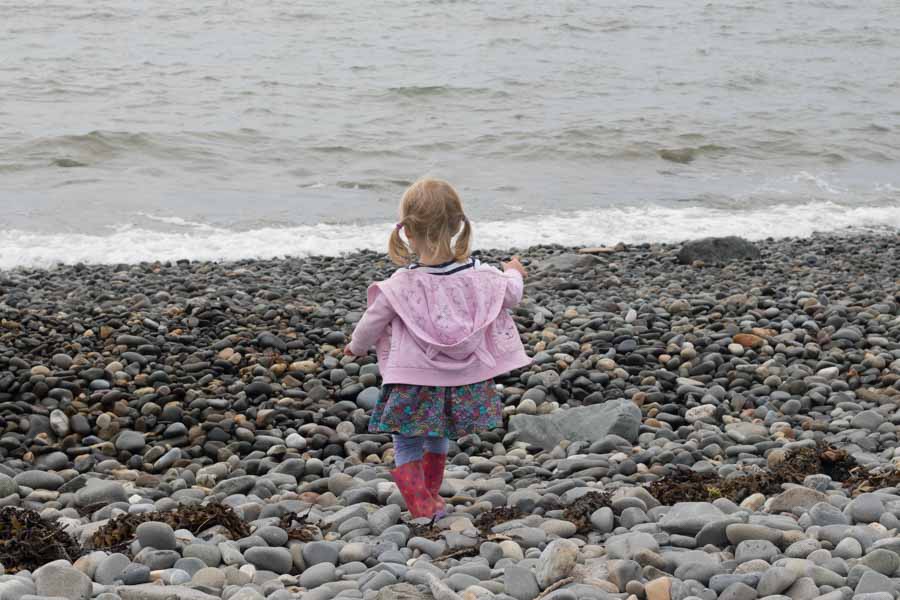 young girl pebble skimming on pebbly beach