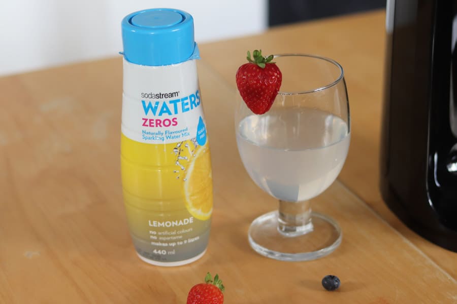 Glass of lemonade next to bottle of waters zeros