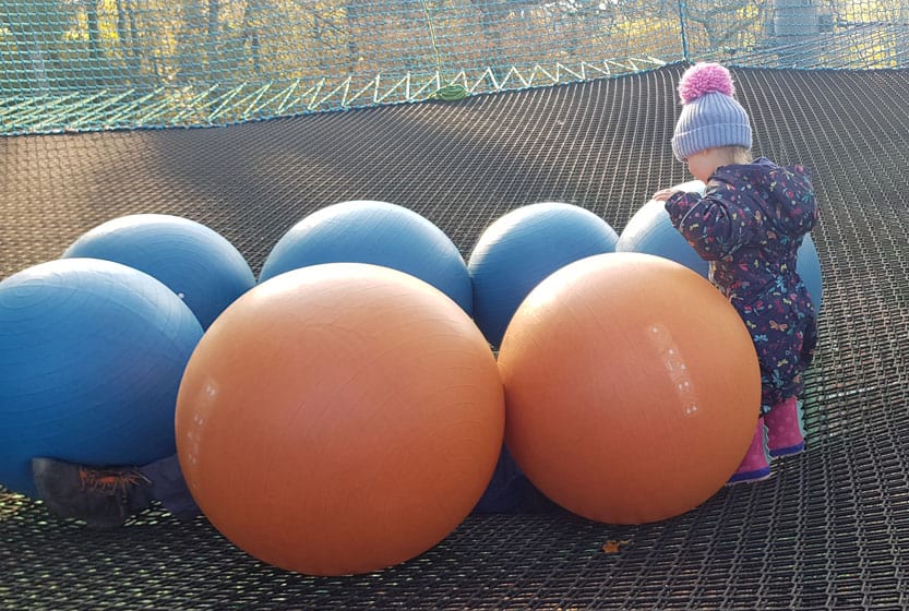 Young child with colourful balls on trampoline
