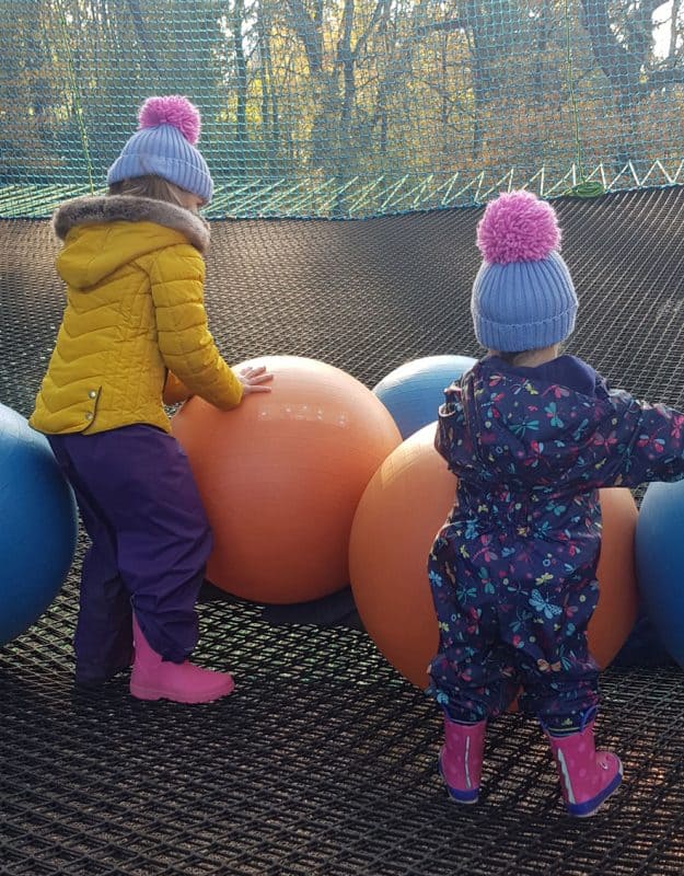 Two children enjoying balls on treep top nets