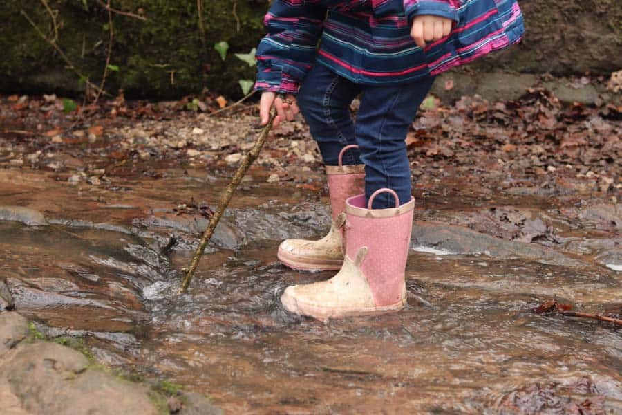 Child stood in a puddle with stick