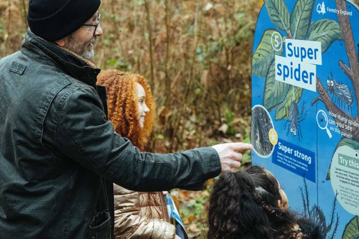 man and children looking at a superworm panel