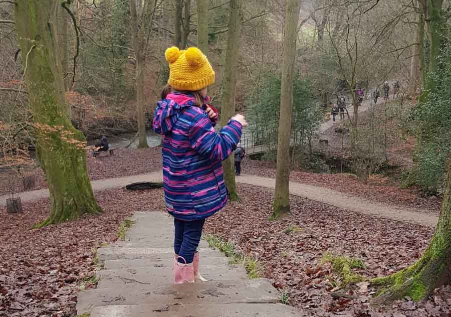 Child dressed for outdoors in winter on woodland walk in Cheshire