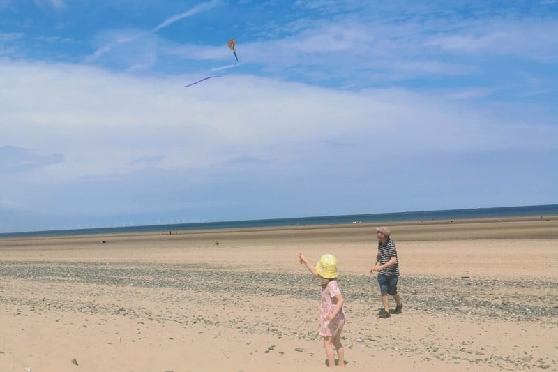 man and child flying a kite on the beach
