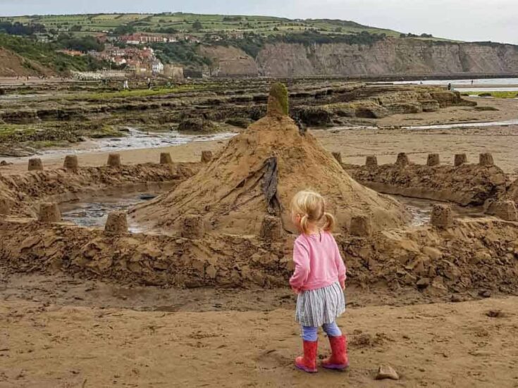 Little girl and a large sand castle