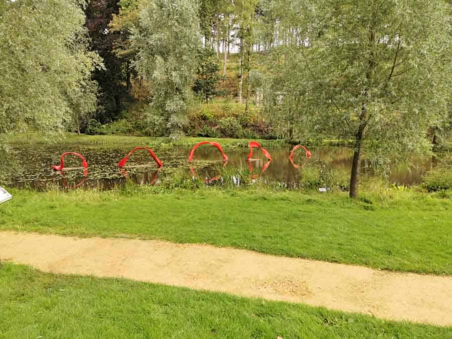 red wave sculpture in a lake