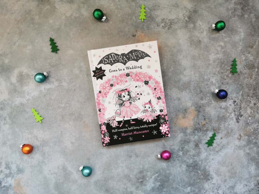 Front cover of the book Isadora Moon goes to a wedding on a stone background with mini christmas decorations