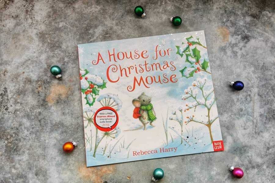 Copy of a house for Christmas mouse, childrens book on a stone background with mini christmas decorations surrounding it