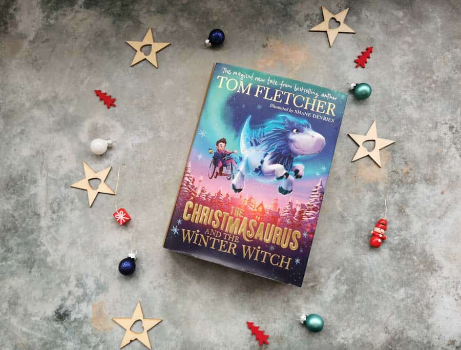 Copy of Christmasaurus and the winter witch childrens book on a stone background with mini christmas decorations surrounding it