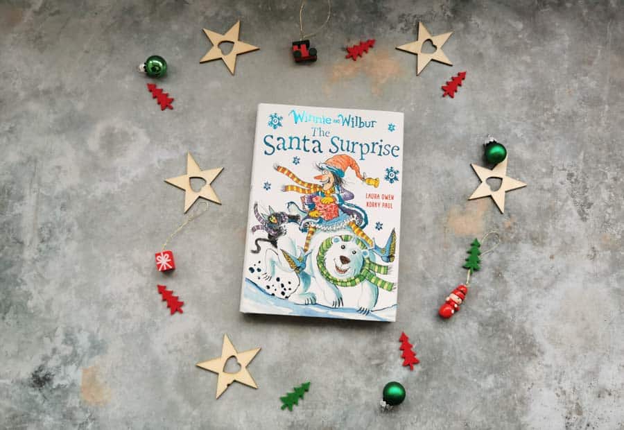 Copy of Winnie and Wilbur and the Santa surprise, childrens book on a stone background with mini christmas decorations surrounding it