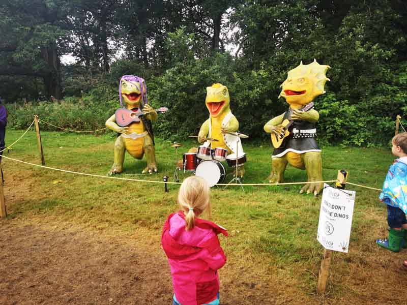 Child looking at three dinosuars dressed like rock stars