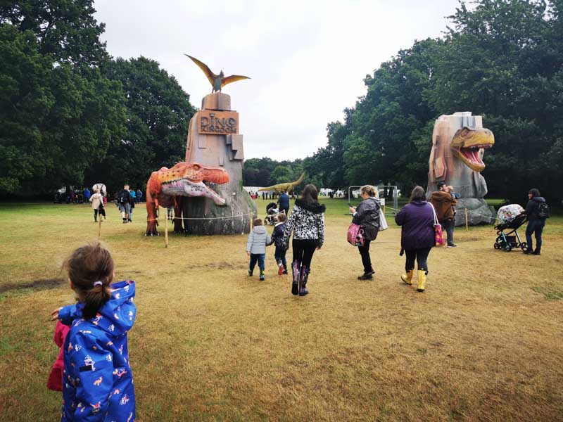 Families walking into Dino Kingdom by two large dinosaurs