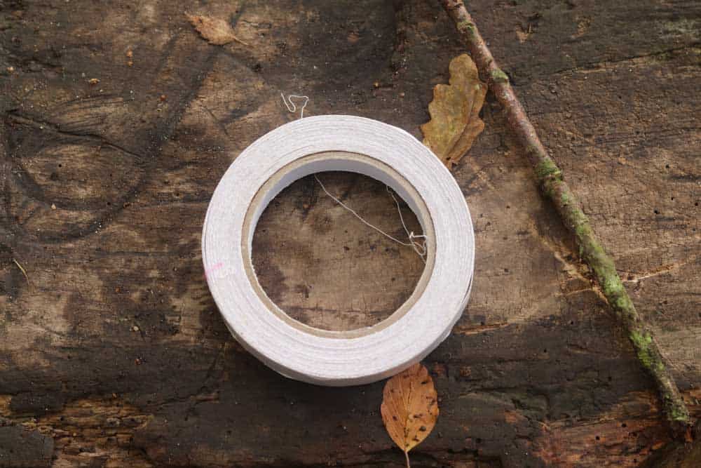 roll of sticky tape and a stick on a log