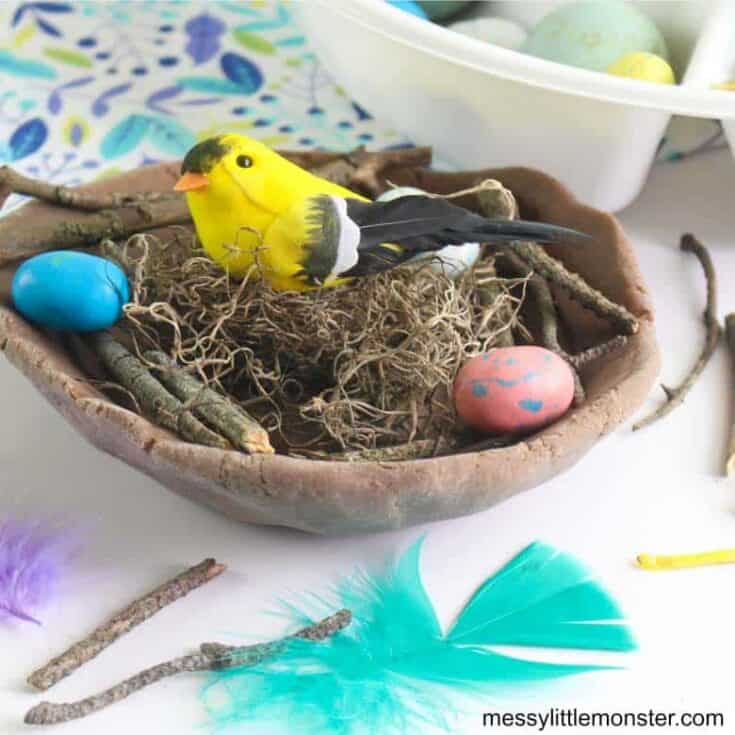 Brown play dough bowl shape filled with twigs and a toy bird
