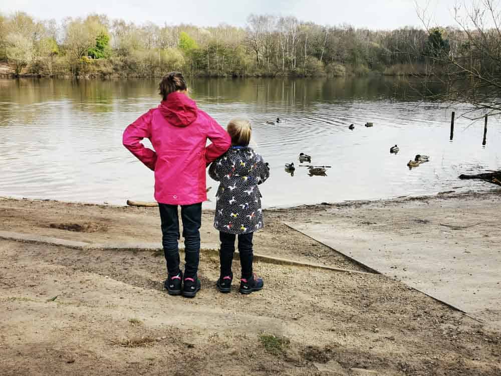 Two girls looking out over a lake wearing waterproof coats