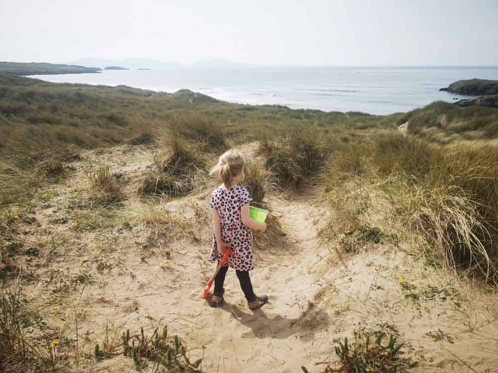 Small girl on the sand dune with bucket and spade