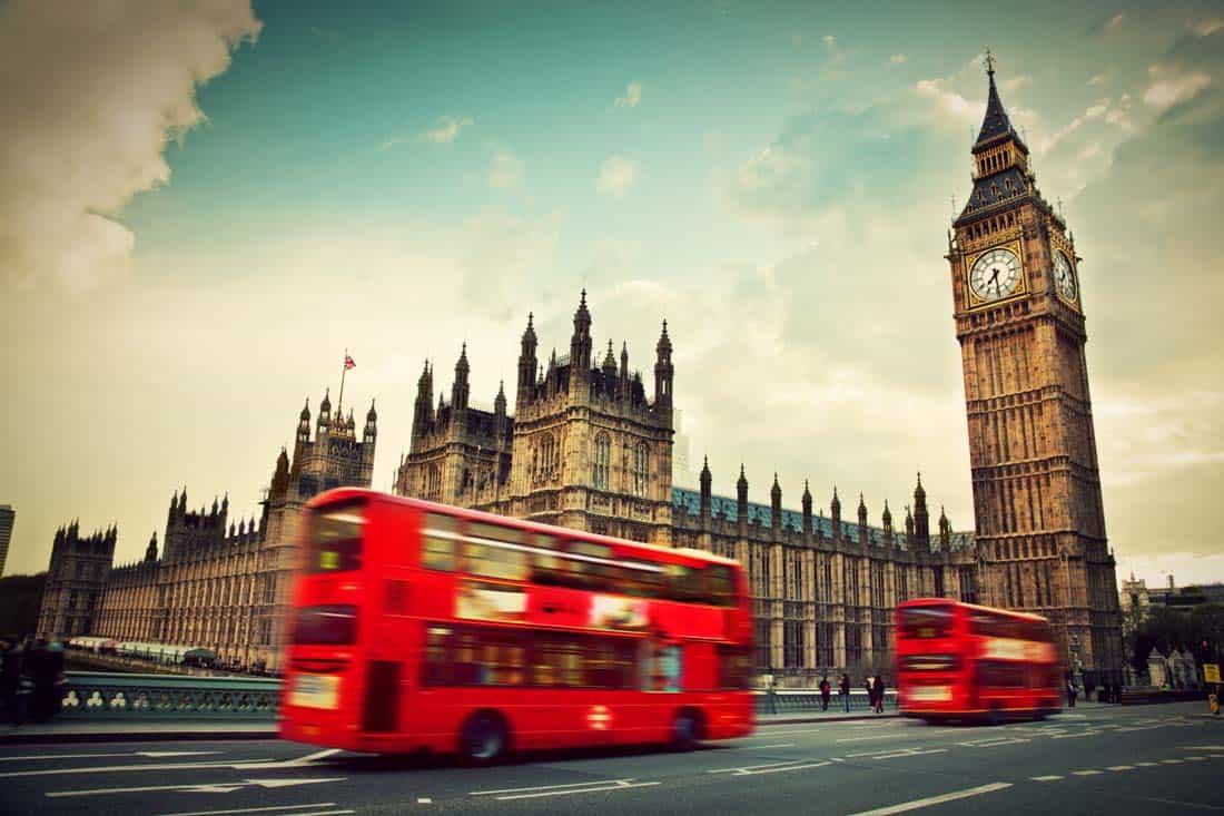 Big ben with red buses going past