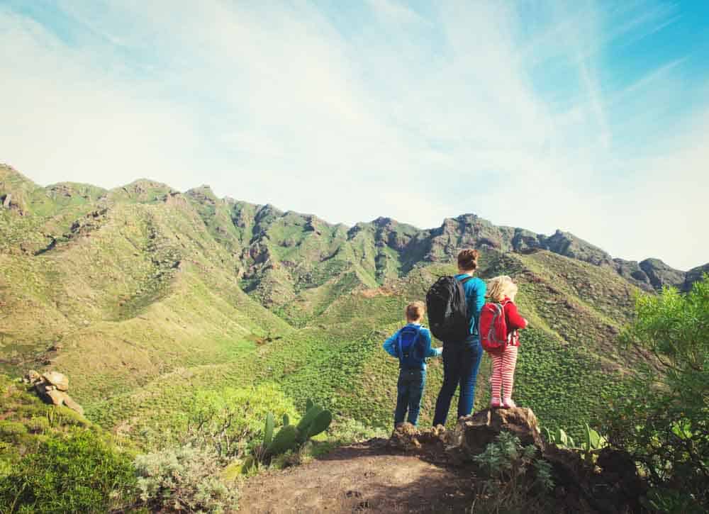 man and 2 kids hiking a mountain