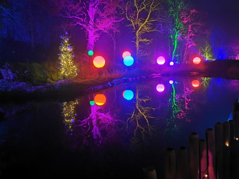 Beautiful, colourful lit up trees and balls reflecting in a lake