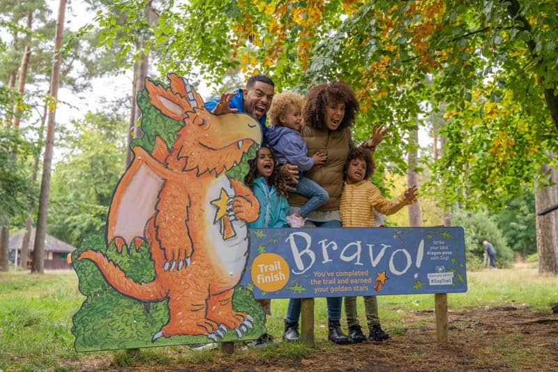 Family stood behind a wooden, large Zog sign