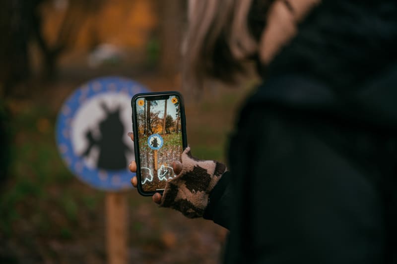 Phone held in front of a sign in the woods