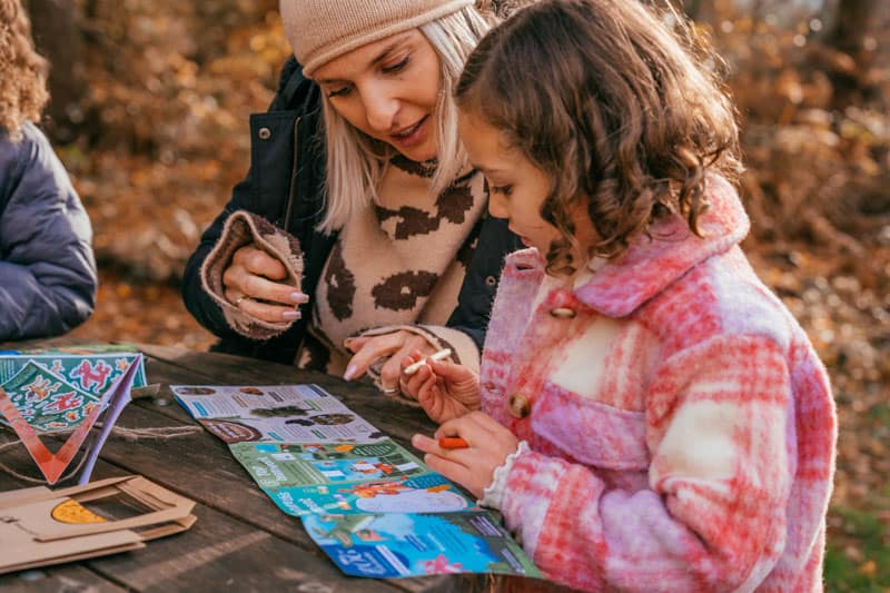 Woman and daughter at a picnic table with an activity sheet