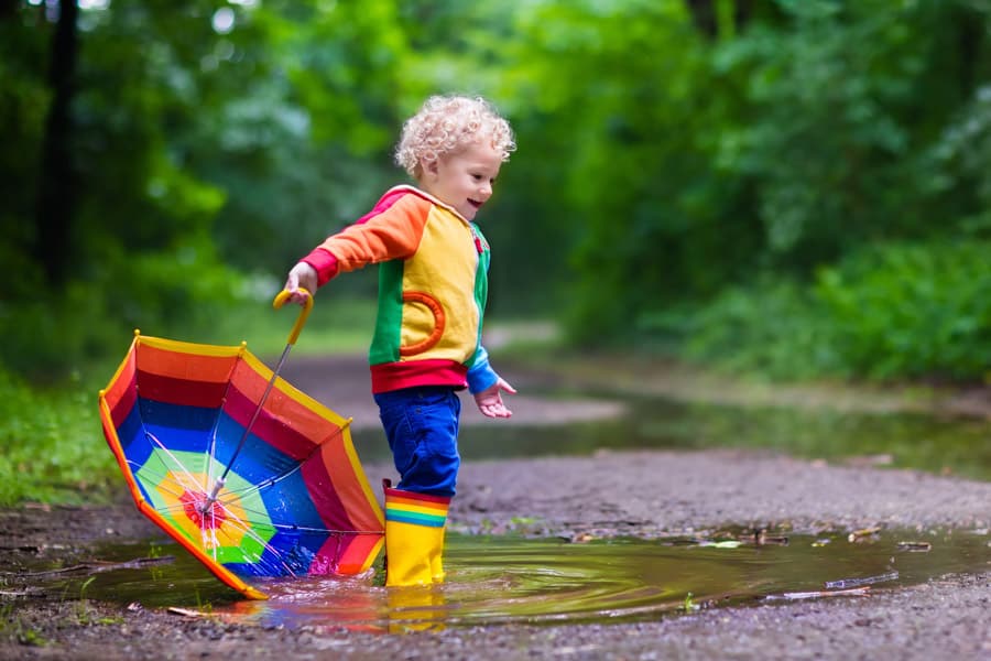 Brightly dressed toddler in a puddle
