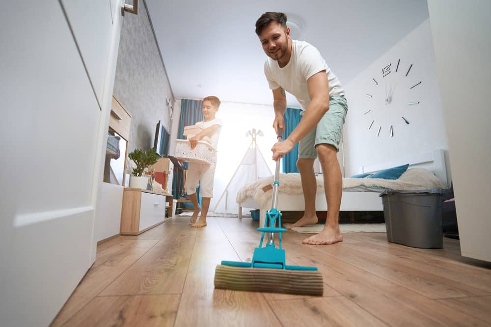 Man mopping floors and child carrying laundry basket