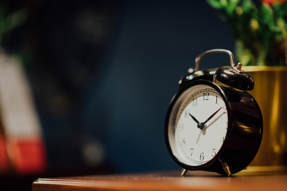 Black traditional alarm clock on a bedside table