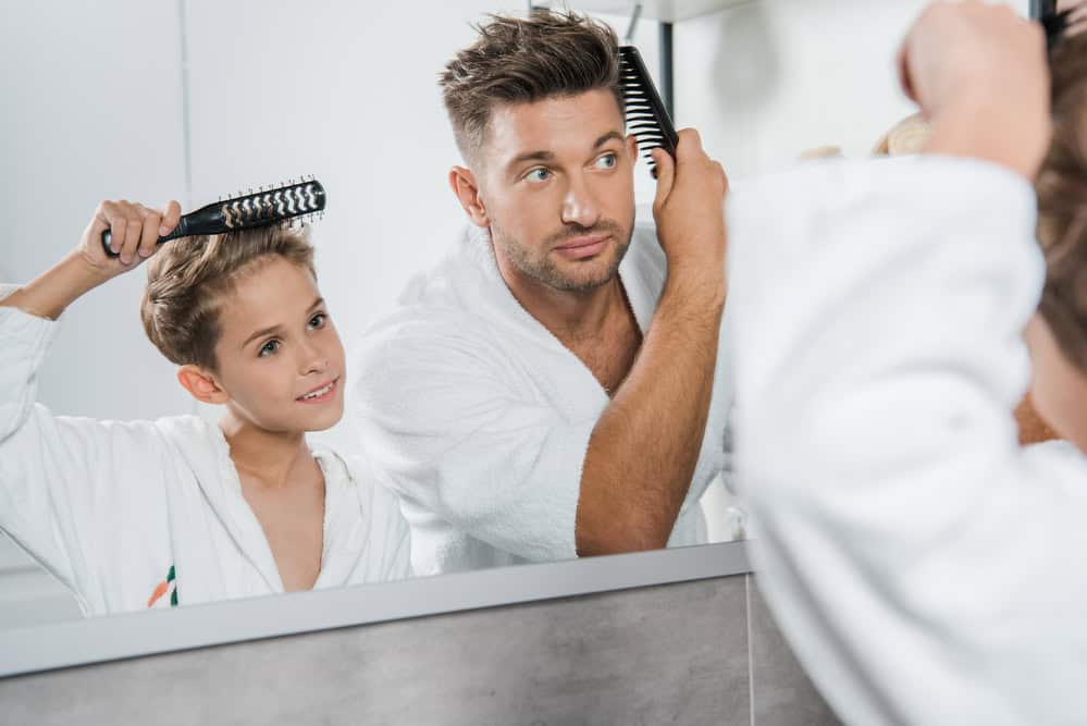 Man and boy combing hair in mirror