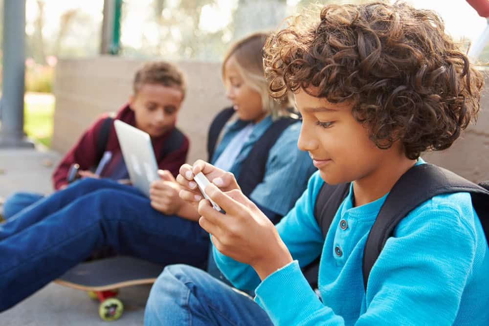 Three children on mobile or laptops
