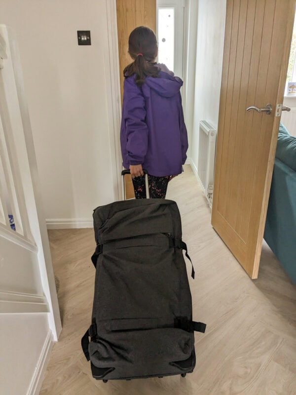 Child pulling a grey holdall along