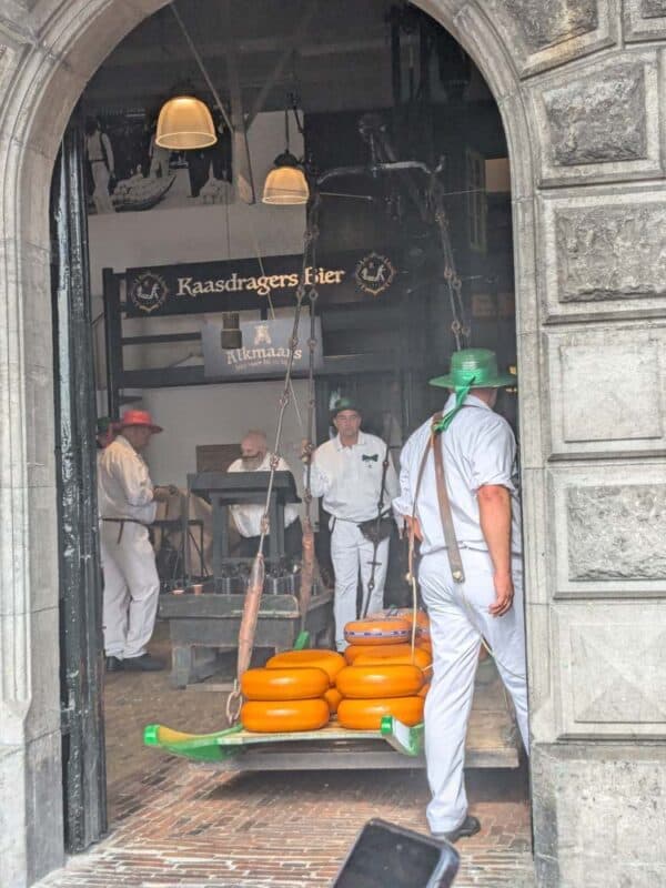 Workers in traditional dress carrying wheels of cheese