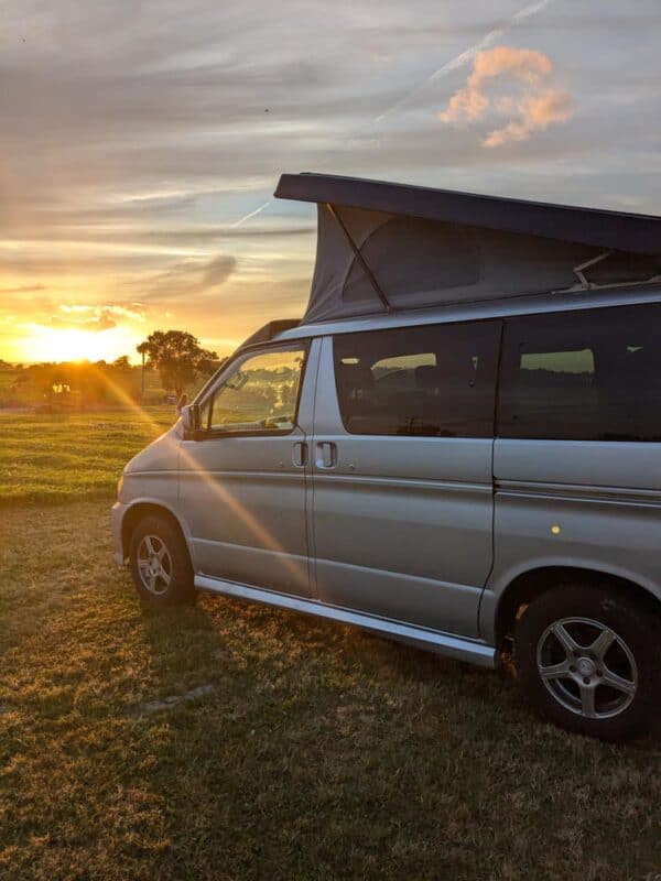 Campervan with pop top up at sunset