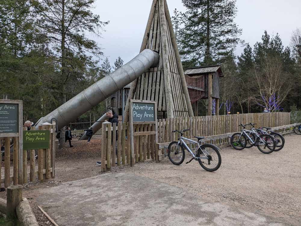 Large wooden adventure playground with tall metal slide