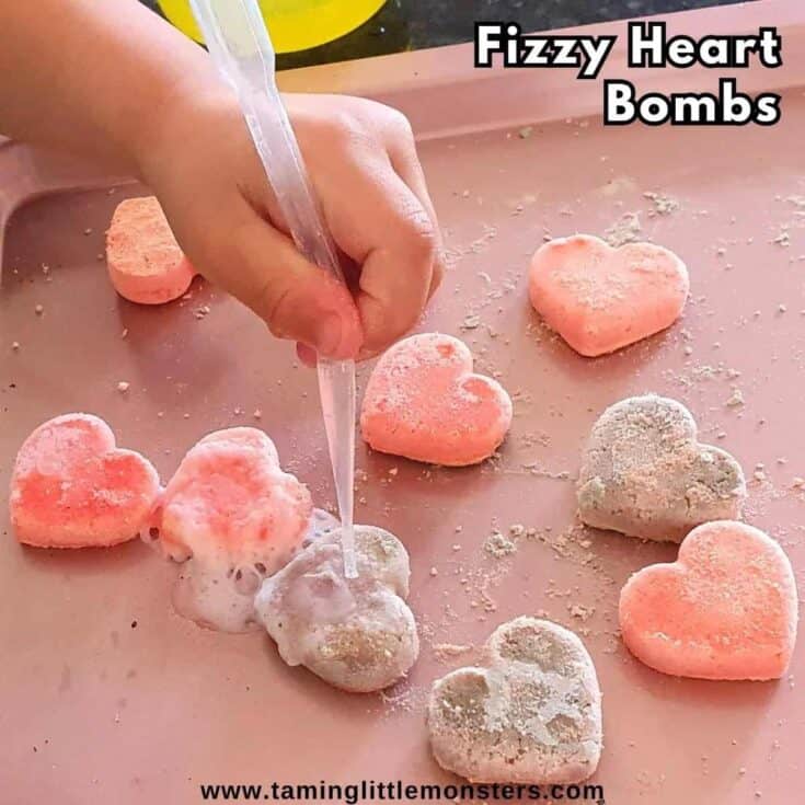 Pink and purple hearts and a child's hand holding a pipette over onw
