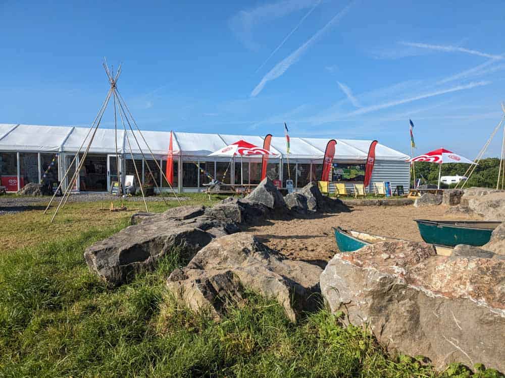 Large sand pit with flags and a marquee behind
