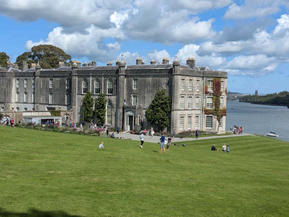 Large grey stone stately home on the egde of water