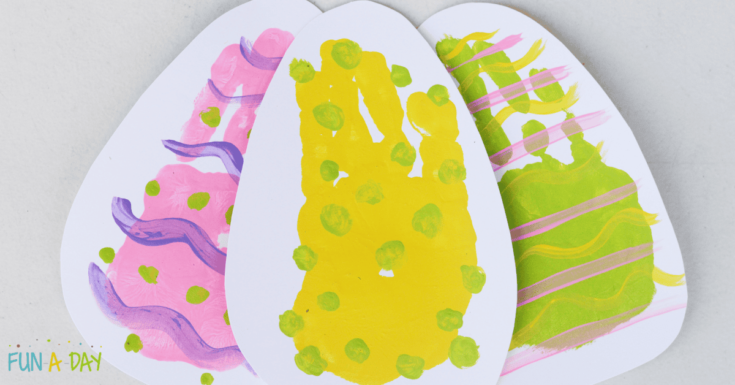 three white egg shapes with colourful handprints