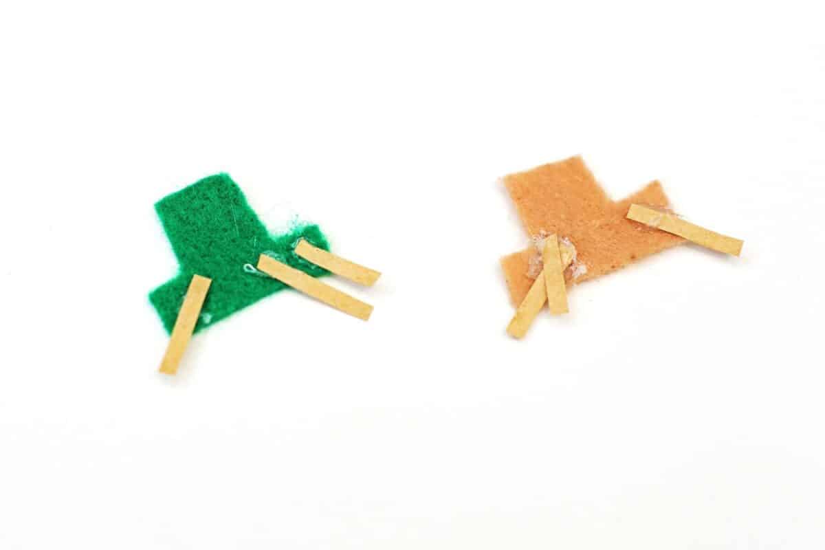 Green and brown felt hat pieces with small strips of straw hair