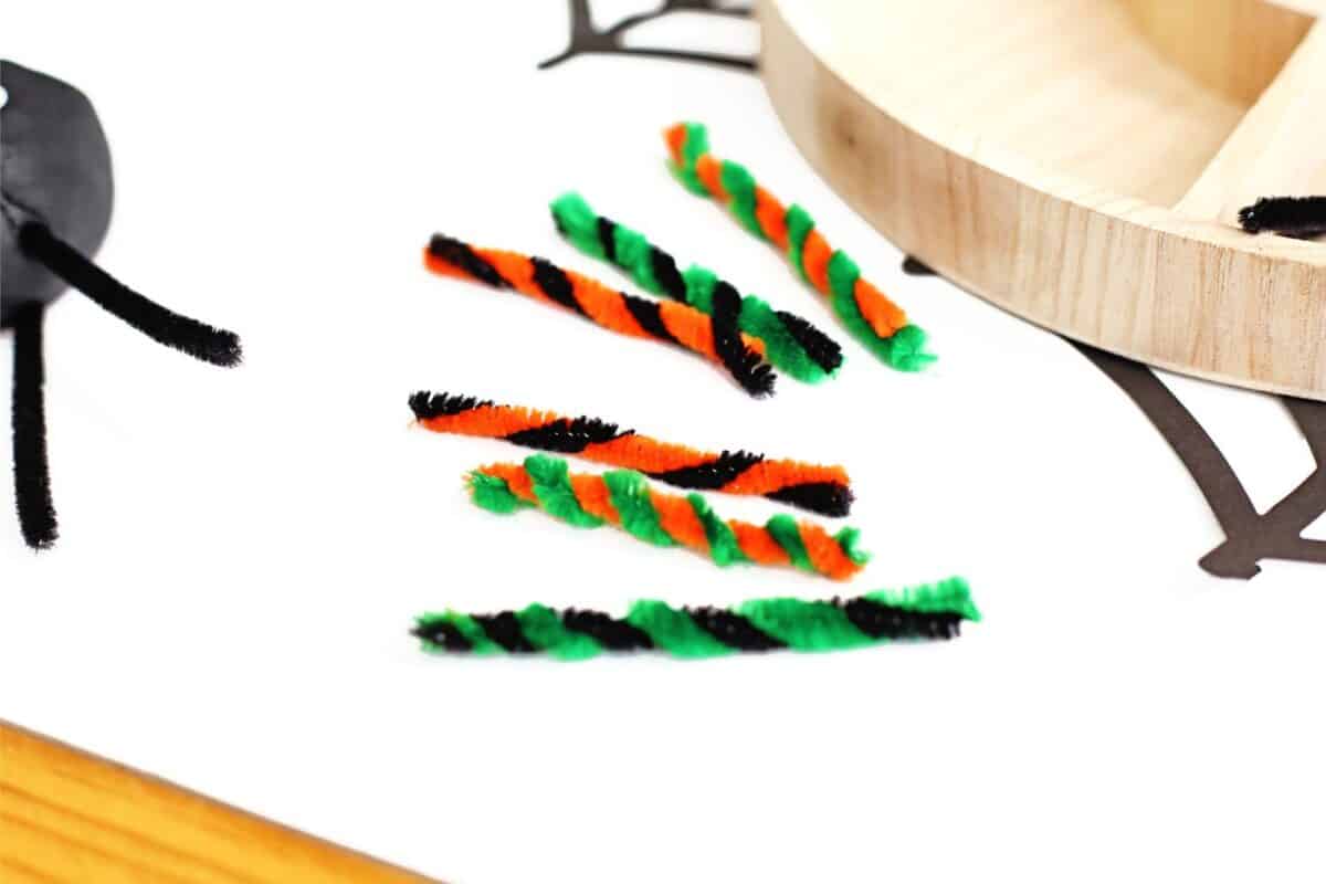 green, orange and black pipe cleaners twisted into spider legs