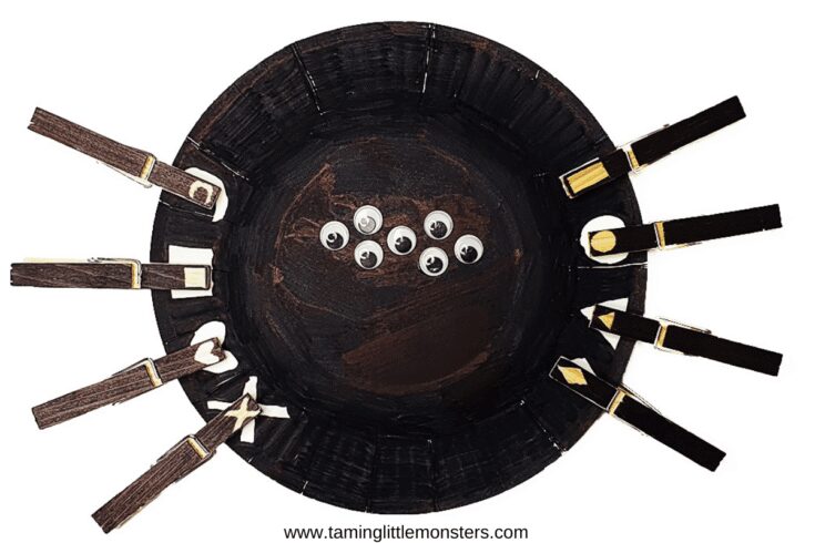 Black paper plate with googly eyes and pegs