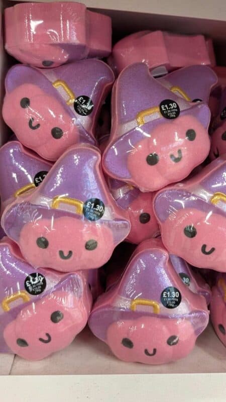 Halloween bath bombs shaped like pink smiling faces wearing purple witch hats