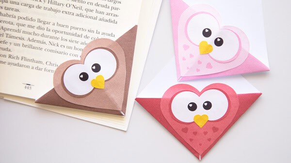 Owl corner bookmark craft for kids made from folded paper in brown, pink, and red designs with big cartoon eyes and yellow beaks.